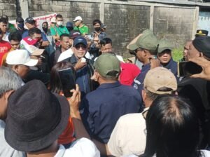 Ket. foto: Advokat Dr. Yafeti Waruwu, SH., MH. (topi dan jaket hitam) ditengah kerumunan massa Eksekusi gudang Margomulyo Surabaya pada Kamis, 4 Juni 2026.